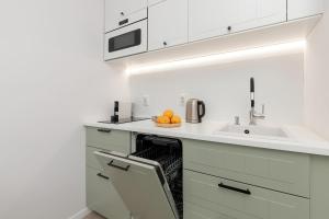 a white kitchen with a sink and oranges on a dishwasher at Studio Śląska z Siłownią w Gdańsku by Noclegi Renters in Gdańsk +7 photos