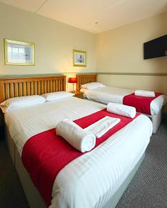 a hotel room with three beds with towels on them at The Western in St Ives