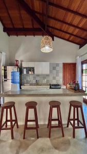 Una cocina con una encimera con tres taburetes. en Casa Morena Luz na Vila de Cumuru, pra fazer tudo a pé! 350m da Praia do Pier!, en Cumuruxatiba