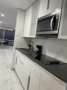 a kitchen with white cabinets and a black counter top at Hermoso Estudio frente al mar Ocean Blue Faith in Fajardo