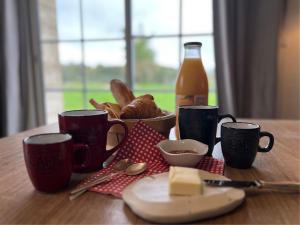 a table with cups and a plate of food and a bottle of soda at La Petite Gendronnière in Fresnes
