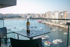 a bottle of wine and two wine glasses on a table at Spinola Seafront Deluxe in St. Julianʼs
