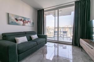 a living room with a green couch and a large window at Spinola Seafront Deluxe in St. Julianʼs
