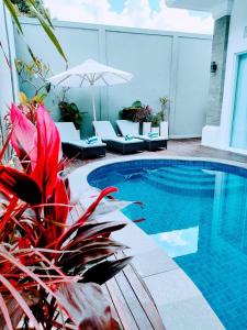 ウルワツにあるVilla Emas Mulia Uluwatu Luxury 6の建物の隣に椅子とパラソルのあるプール