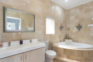 a bathroom with a sink and a toilet and a tub at Sea View Hilltop Villa, Blouberg in Cape Town +34 photos