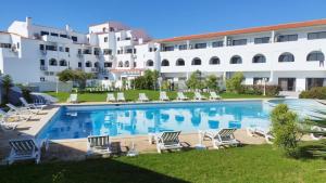 einem großen Pool mit Liegestühlen vor einem Gebäude in der Unterkunft Cozy Apartment in Sagres in Sagres