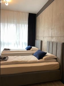two beds in a room with a window at Nowoczesne Apartamenty Stare Miasto in Częstochowa