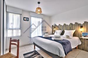 a bedroom with a large bed and a chair at LocaLise - A02 - Appartement de plain-pied - terrasse - Juste à côté de la plage - Centre et port à pied - Wifi inclus - Draps inclus - Animaux bienvenus in Tréffiagat