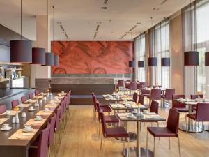 a dining room with long tables and purple chairs at IntercityHotel Leipzig in Leipzig