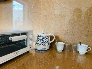 a tea kettle and cups on a counter next to a microwave at Cozy House in Rose Hill