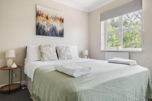 a white bedroom with a large bed with two pillows at Modern & Comfortable with Free Parking in Bedford