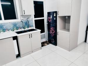 une cuisine avec des armoires blanches et un réfrigérateur dans l'établissement Zenith Paradise-Luxurious 3BR Apartment, à Hyderabad