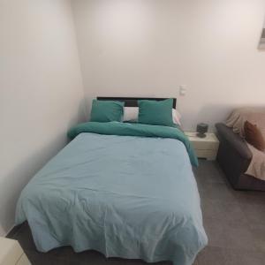 a bedroom with a bed with blue sheets and a couch at Petite maison avec jardin in Montluçon