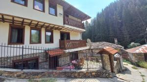 ein Haus mit einem Balkon an der Seite in der Unterkunft Къща за гости Начовата къща, Стойките, община Смолян in Vodata