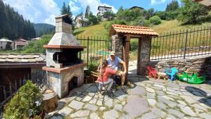 a man and a woman sitting in front of a fireplace at Къща за гости Начовата къща Стойките, Пампорово in Vodata +95 photos