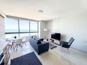 a living room with a couch and a table at Ilanga Africa Beach Front Apartments in Cape Town