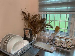 a kitchen counter top with dishes and a window at Indah Jerai Homestay in Guar Chempedak
