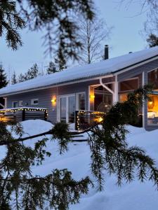 a house in the snow with lights on it at Villa Laidike with sauna/fireplace, 80 km Helsinki in Suomusjärvi