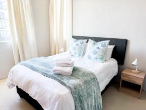 a bedroom with a bed with towels on it at Ilanga Africa Beach Front Apartments in Cape Town +12 photos