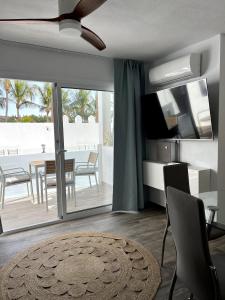 a living room with a television and a table and chairs at Las Palmeras del Sol in Tarajalejo