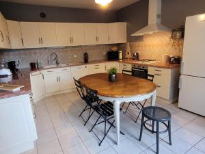 Pocé-sur-CisseにあるLa maison aux irisのテーブルと椅子と冷蔵庫のあるキッチン