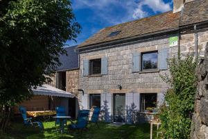 an old stone house with blue chairs in the yard at Gîte La Peyrade d'Aubrac 6/8 personnes in Marchastel