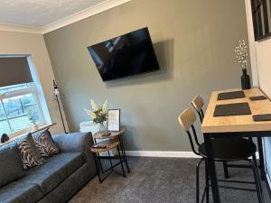 a living room with a couch and a tv on the wall at Walnut House - Modern 1 Bedroom Apartment very close to town by Shortstays4u in Kings Lynn +2 photos