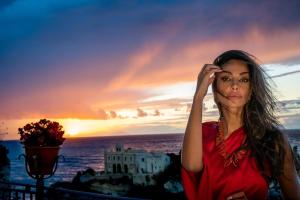 a woman standing in front of the ocean at sunset at La Dolce Vita a Tropea in Tropea