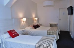 a hotel room with two beds and a red pillow at Hotel Don Carlos in Villa Gesell