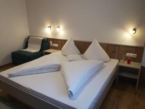 a bed with white pillows and a chair in a room at Ferienchalet HOLDERNACH in Kappl +17 photos