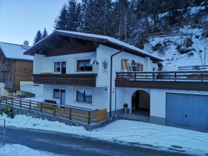 a white house with a balcony in the snow at Ferienchalet HOLDERNACH in Kappl