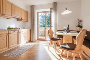 una cocina con armarios de madera, mesa y sillas en Der Mittermoar, en Bresanona