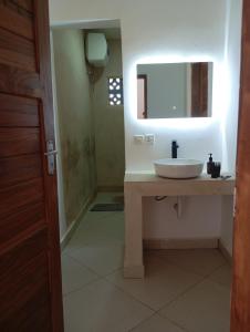 a bathroom with a sink and a mirror at Aluna Beach House Nungwi in Nungwi