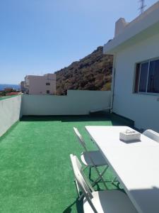 una mesa blanca y sillas en un balcón con césped verde en Vero Housing, en María Jiménez