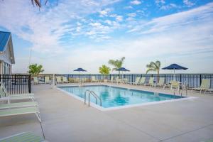 ein Swimmingpool mit Stühlen und Sonnenschirmen in der Unterkunft Blufin Bungalows & Marina in Chincoteague