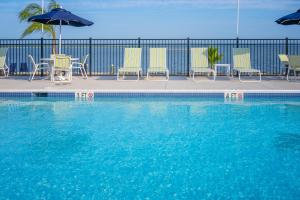 ein Swimmingpool mit Stühlen und Sonnenschirmen neben in der Unterkunft Blufin Bungalows & Marina in Chincoteague