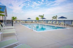 ein Swimmingpool mit Stühlen und Sonnenschirmen und das Meer in der Unterkunft Blufin Bungalows & Marina in Chincoteague