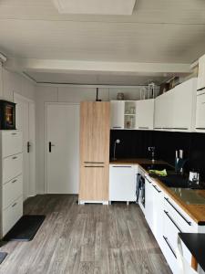 a kitchen with white cabinets and a wooden floor at Strefa relaxu u JJ in Powałki