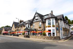 un edificio con mesas y sombrillas en una calle en McKays Hotel, en Pitlochry