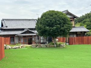 una casa con un albero di fronte a un cortile di いろどり荘 ドッグラン併設 露天風呂付き a Inokuchi