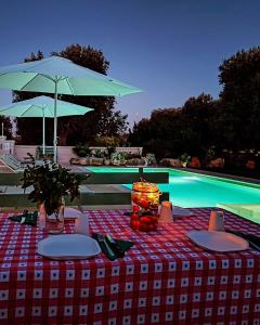 a table with a blue umbrella next to a pool at La casa nel villaggio in Montalbano