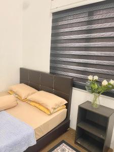 a bedroom with a bed and a vase of flowers at D'inaa Homestay Kota Bharu in Kota Bharu +2 photos