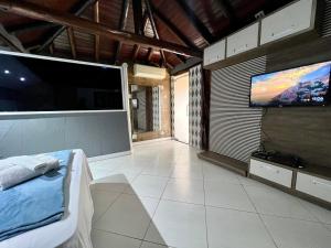 a living room with a large screen tv and a bed at Espaço Verano - Suíte Master 2 in Niterói