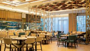 a restaurant with tables and chairs under a chandelier at Le Meridien Amritsar in Amritsar