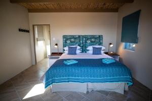 a bedroom with a large bed with blue pillows at De Mond Villa in Bredasdorp