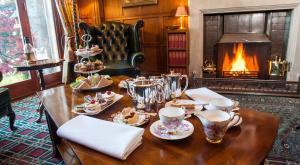 uma mesa com copos e pratos de comida e uma lareira em Tigh na Sgiath Country House Hotel em Grantown-on-Spey