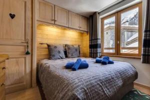 a bedroom with a large bed with blue pillows at Chalet Ancolie 2e Appartement cosy dans un chalet in Val dʼIsère