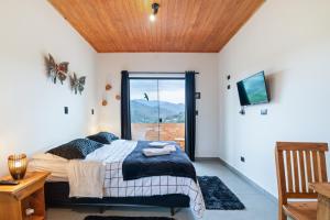 a bedroom with a bed and a tv and a window at Studios Pinhal in Santo Antônio do Pinhal