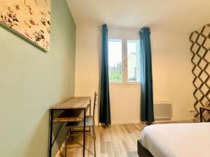 ein Schlafzimmer mit einem Schreibtisch und einem Bett und einem Fenster in der Unterkunft Le Guillaumin, convivial et zen in Limoges