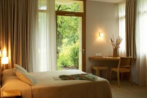 a bedroom with a bed and a desk and a window at Hôtel Les Esclargies in Rocamadour